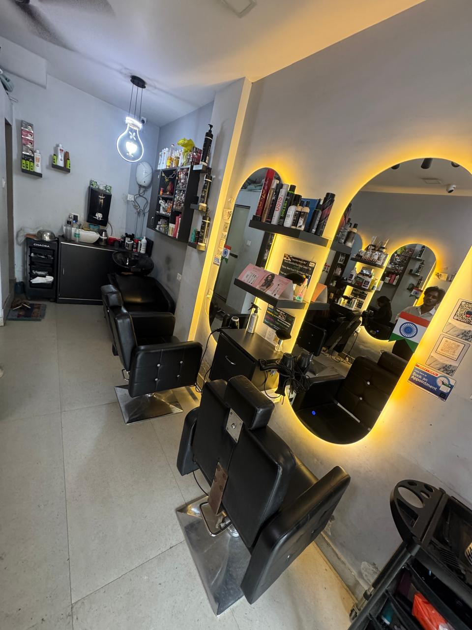 Salon floor with black styling chairs and arched lit mirrors